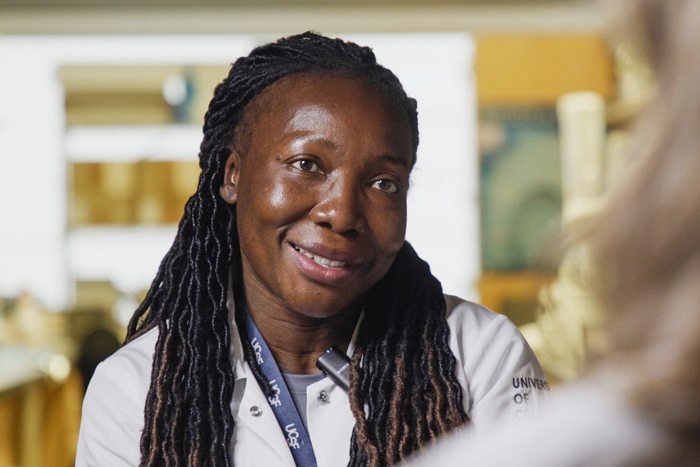 Dr. Melsa Omaya in a UCSF lab coat, smiling in conversation.