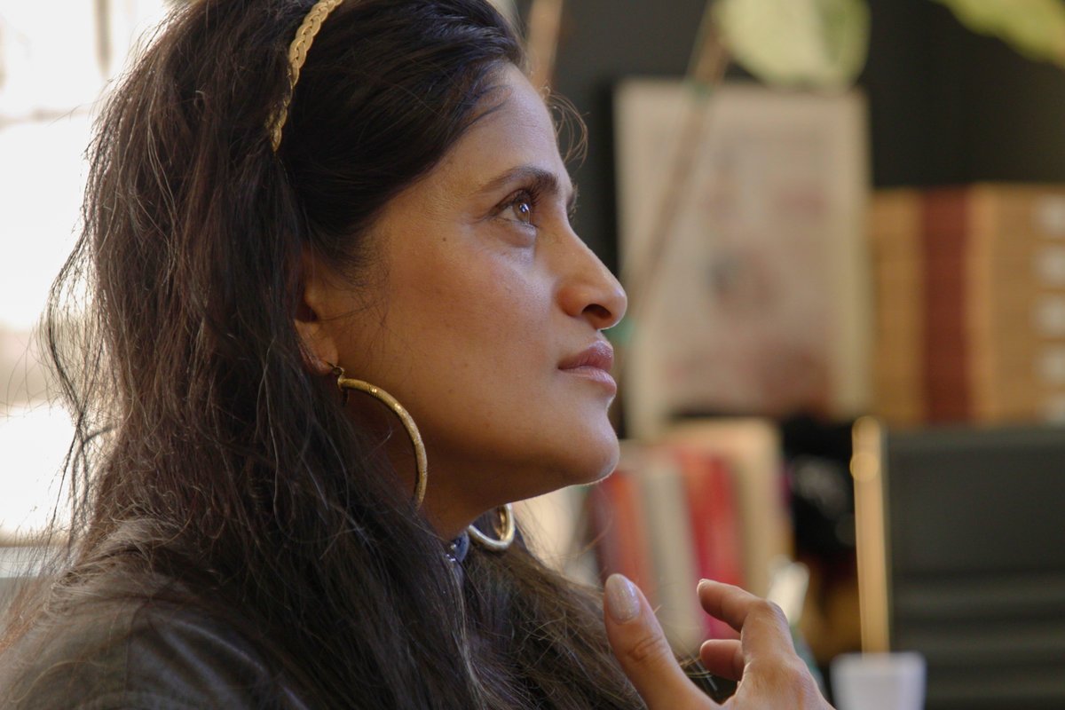 Ridhi Tariyal in profile, listening, in a book-lined room.